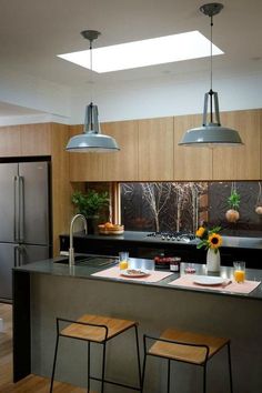 a kitchen with two stools next to an island and breakfast bar in the middle