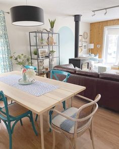 An open-concept living and dining space has a unique character with a vintage wood-burning stove and a vertical shiplap wood accent wall. Add a cute cottage-inspired wood dining table with brightly colored wood chairs and cushions, and complement the set with a brightly colored flower arrangement centerpiece...   Image: yzfhomedecor