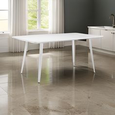 a white table sitting in the middle of a room next to a sink and window