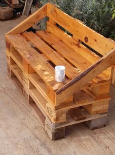 a wooden bench made out of pallets with a cup on the seat and some trees in the background