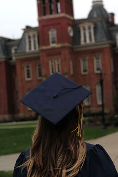 a woman wearing a graduation cap and gown in front of a large red brick building