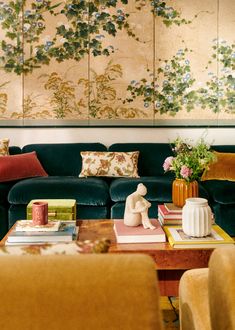 a living room filled with lots of furniture next to a wall covered in flowers and paintings