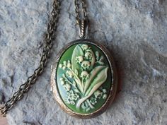 "Beautiful cameo locket The cameo is a gorgeous lily of the valley. Stunning colors, each cameo is individually hand painted and antiqued, each an original The bronze ans silver plated lockets are victorian style with beautiful scroll on both the front and back about 2\" long. They can hold two photos or a treasured keepsake. Pass down from generation to generation The bronze locket includes a 24\" adjustable rolo link chain with a lobster claw clasp, and the silver includes a 22\" .925 silver p Etiquette Vintage, Funky Jewelry, April 26, Coin Jewelry, Jewelry Inspo, Dream Jewelry, Locket Necklace, Pretty Jewellery, Lily Of The Valley