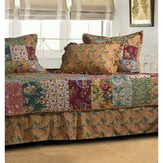 the bed has many pillows on it and is made with colorful fabric, along with decorative wall hangings