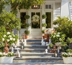 the front porch is decorated with white flowers and greenery, including potted plants