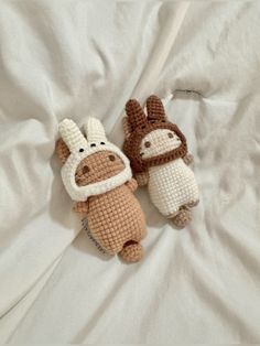 two crocheted stuffed animals laying on top of a bed