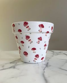 a white bowl with red mushrooms on it sitting on top of a marble countertop