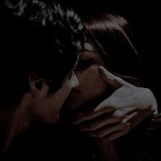 two people are kissing in the dark with their hands on each other's face