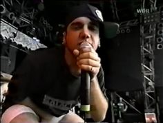 a man holding a microphone up to his mouth while sitting in front of a stage