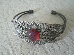 This beautiful silver plated filigree cuff bracelet has a silver plated triple moon design and a glass dragon's breath fire opal setting. Adjustable. Adjustable Mystical Silver Bracelet, Adjustable Silver Mystical Bracelet, Silver Gothic Bracelets For Festival, Adjustable Fantasy Bracelets As Gift, Silver Fantasy Jewelry For Festivals, Handmade Silver Gothic Bracelet, Handmade Silver Gothic Bracelets, Nickel-free Fantasy Jewelry For Festivals, Handmade Gothic Silver Bracelets