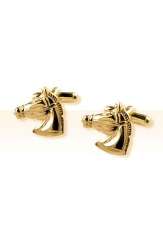 two gold cufflinks with horse heads on them