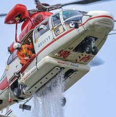 a red and white helicopter flying through the air with people in it's cockpit