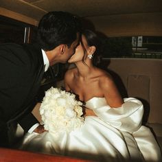 a bride and groom kissing in the back of a car