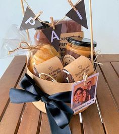 a basket filled with bread and jams on top of a wooden table