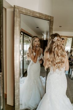 the bride is looking at her reflection in the mirror