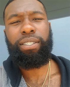 a close up of a person with a beard wearing a hoodie and gold necklace