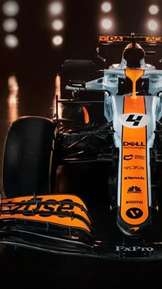 an orange and white race car with lights in the background