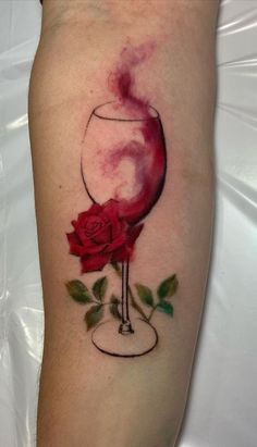 a woman's arm with a wine glass and rose tattoo on it