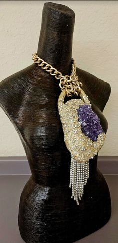 Here's a piece I had forgotten to list. A set a rough purple amethyst into a baroque style sculpture, painted it metallic gold and then heavily studded it with rhinestones. An angled silver tone rhinestone fringe sways from the bottom left hand corner which gives additional drama to the piece. The pendant measures 12" x 4" from the bail to the bottom of the rhinestone fringe. A warm gold large cable link chain suspends the piece and has an approximate 9" drop on each side. It closes with an xl f Luxury Purple Jeweled Jewelry, Luxury Purple Jewelry For Collectors, Purple Crystal Jewelry With Stones, Artisan Amethyst Jewelry With Stones, Luxury Purple Stone Jewelry, Luxury Purple Jewelry With Stones, Amethyst Gemstone Jewelry For Parties, Unique Purple Collectible Jewelry, Unique Purple Jewelry With Gemstone Accents