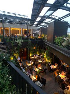 an outdoor dining area with tables and people sitting at the tables in front of them