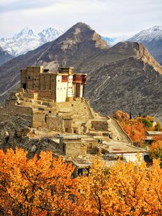 an old building on top of a mountain surrounded by trees and mountains in the background