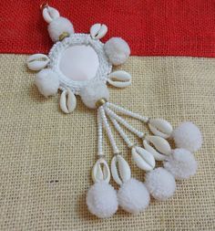 a white necklace with pom - poms hanging from it's sides on a red and beige surface