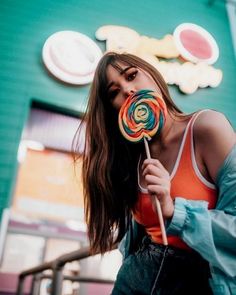 a woman holding a lollipop in front of a building