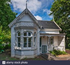 an old victorian style house in the middle of a park with trees and bushes around it