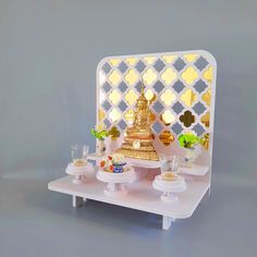 a white table topped with plates and cups filled with food next to a golden buddha statue