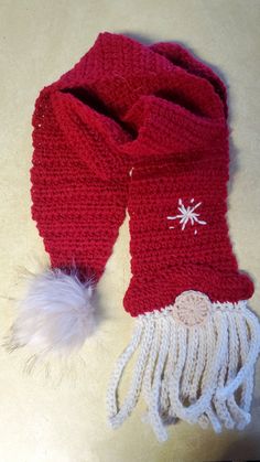 a knitted scarf with white and red decorations on it, sitting on a table