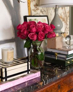 a vase filled with pink roses sitting on top of a table next to two books