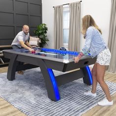 two people playing foo - pong in a living room with a couch and coffee table