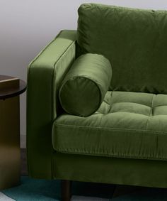 a green couch sitting on top of a blue rug next to a table with a lamp