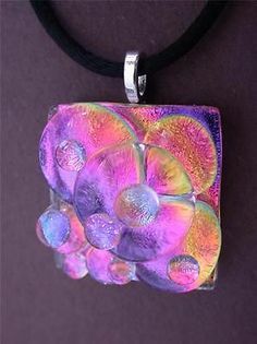 a glass pendant is hanging on a black cord with an orange and pink flower in the center