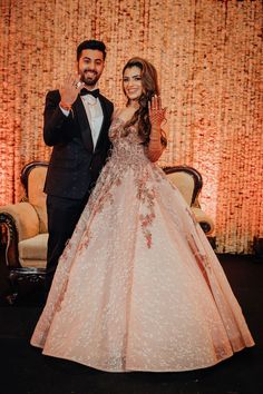 the bride and groom pose for a photo in front of a backdrop with red flowers