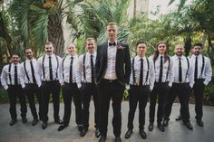 a man in a tuxedo standing with his groomsmen and bridesmaids