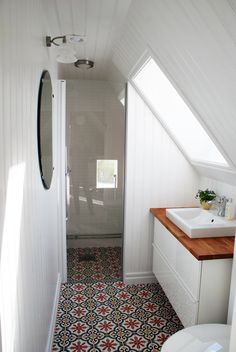 a bathroom with a sink, toilet and shower stall in it's attic space