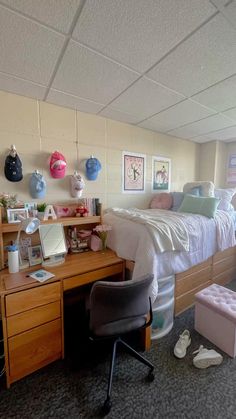 a bedroom with a bed, desk and chair in it next to a wall that has pictures on it