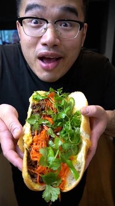 a man holding up a sandwich filled with veggies