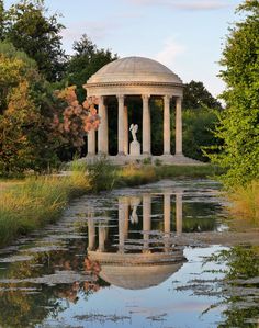 a gazebo in the middle of a pond surrounded by trees