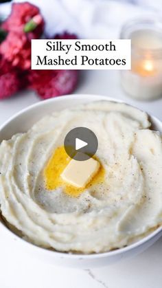 a bowl filled with mashed potatoes on top of a white table next to candles