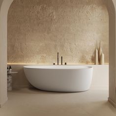 a large white bath tub sitting next to a stone wall in a room with arches