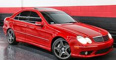 a red mercedes benz coupe parked in a garage