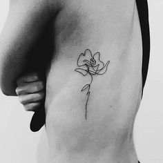 a black and white photo of a woman's back with a flower tattoo on it