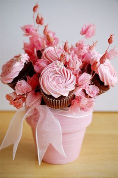 a cupcake decorated with pink flowers in a vase