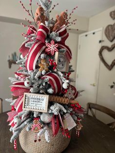 a decorated christmas tree with candy canes and ornaments on it's top, sitting on a table