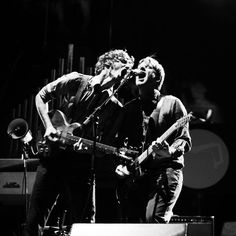 two young men are playing guitars on stage