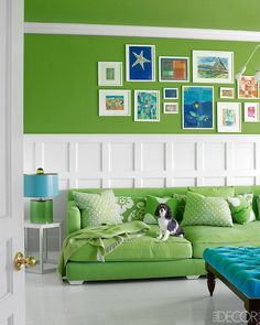 a living room filled with green furniture and pictures on the wall above it's headboard