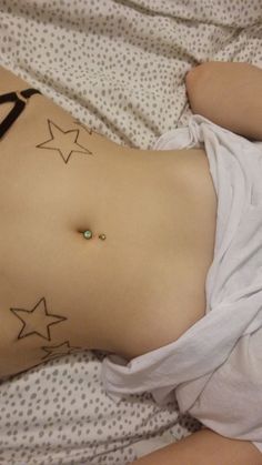 a woman laying on top of a bed with tattoos on her stomach and under the belly