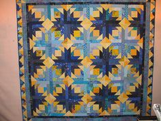 a blue and yellow quilt hanging on the wall